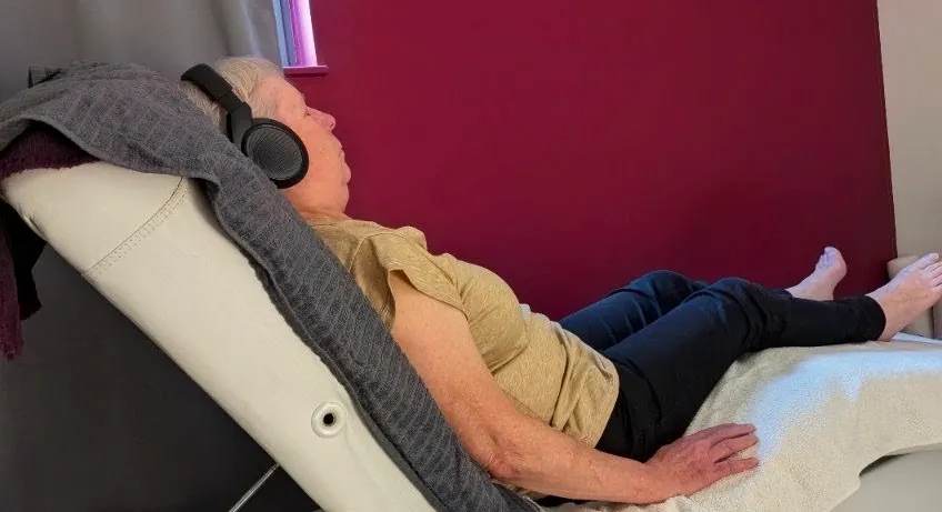 Séance d'hypnose Ericksonienne : une patiente détendue dans un fauteuil de relaxation inclinable, casque audio sur les oreilles
